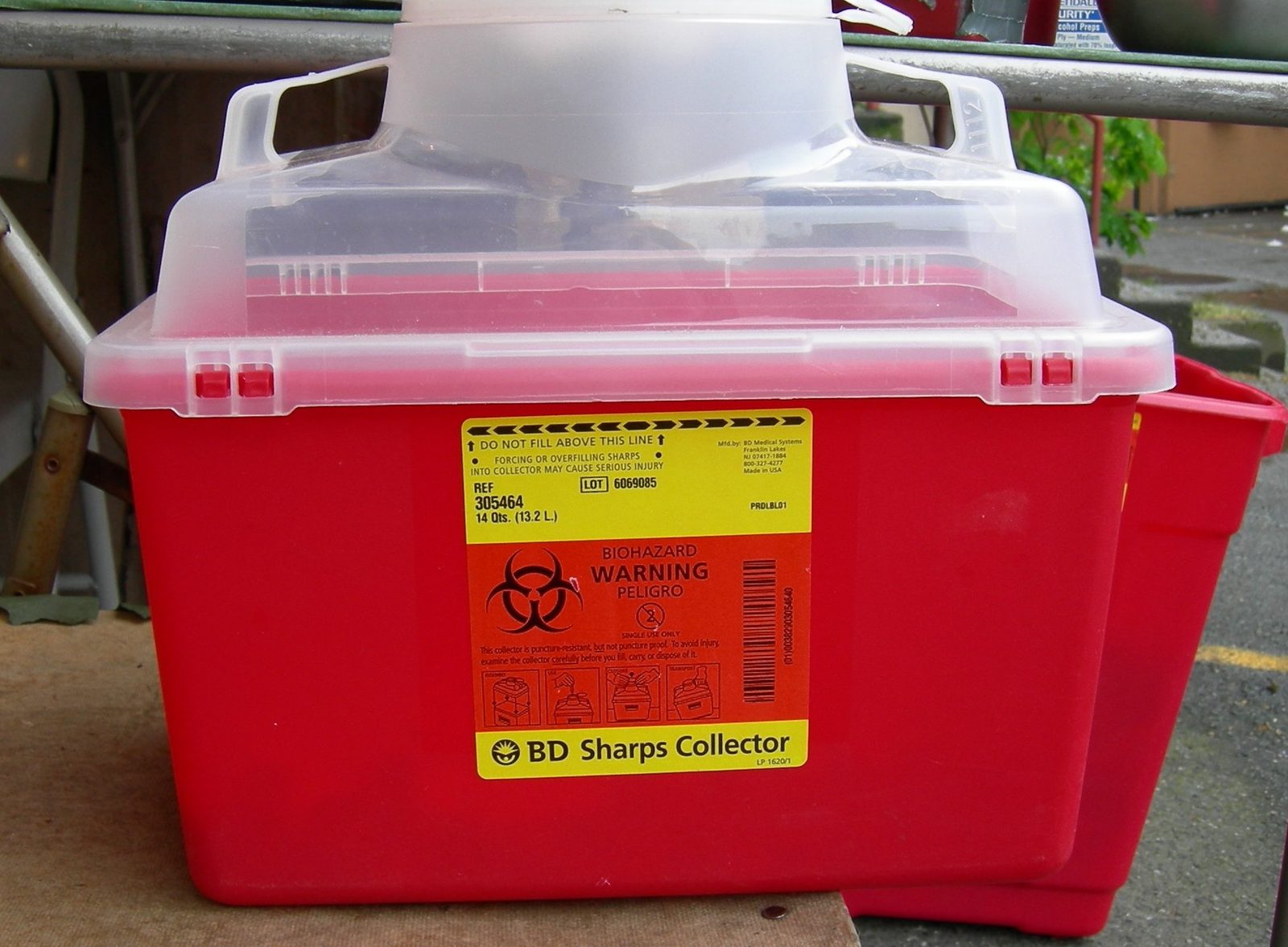 Red biohazard sharps container with a fill line and BD Sharps Collector label