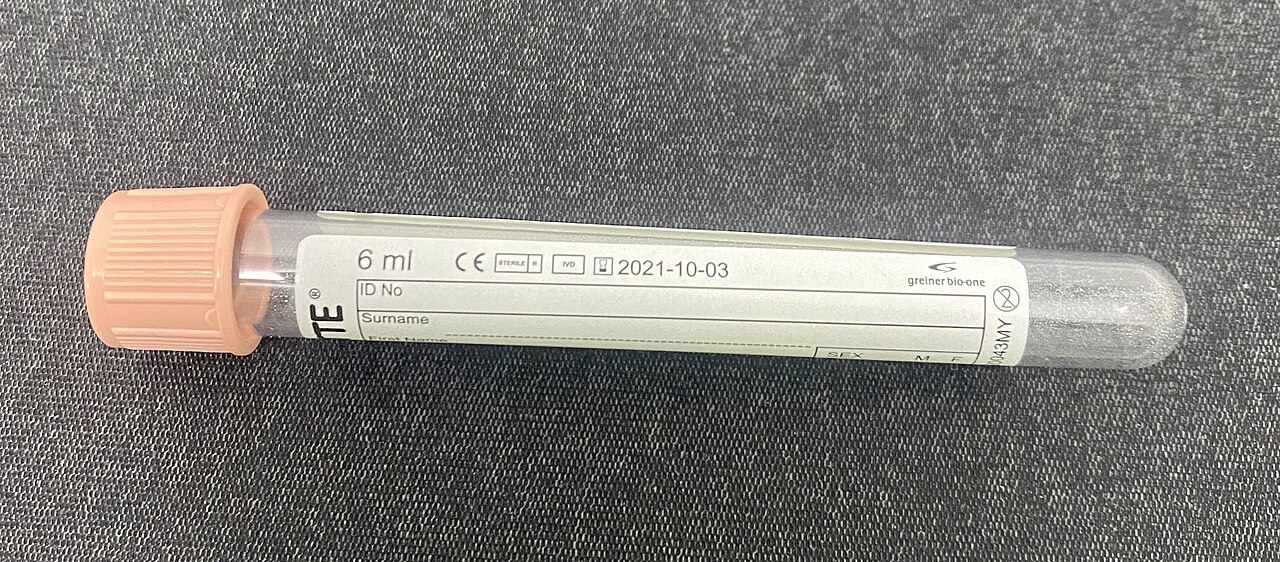 An unused pink-capped collection tube with blank ID and surname fields and manufacturer information.