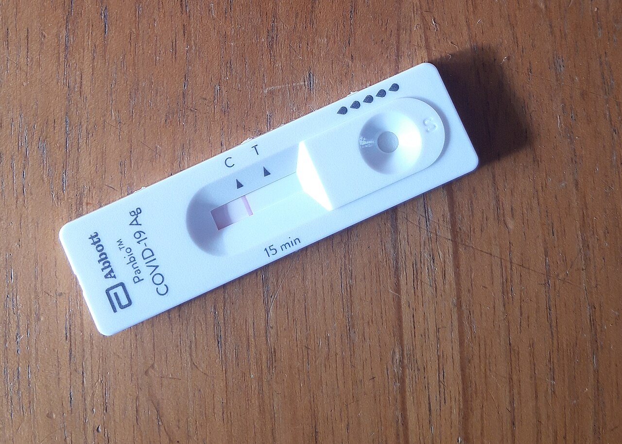 A COVID-19 antigen-test cassette has a sample well, a result window, and printed C and T position markings.